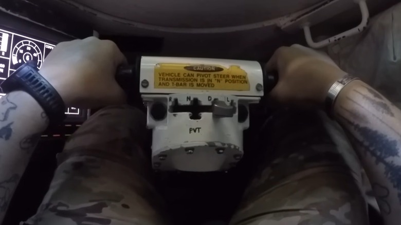 The control yoke of the M1A2 Abrams MBT with a Soldier sitting in the driver's seat