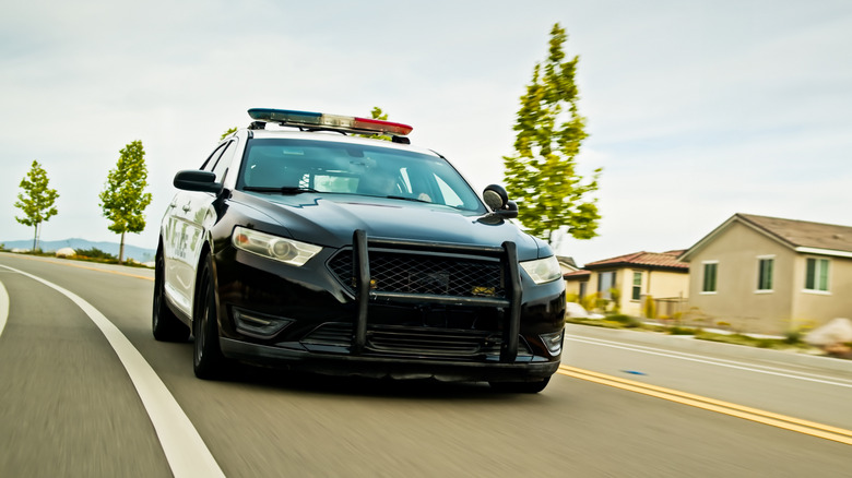 Police car driving down suburban neighborhood