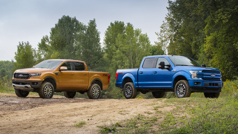 Ford Ranger and Ford F-150 parked side-by-side facing away from one another on a dirt road, Ranger on left