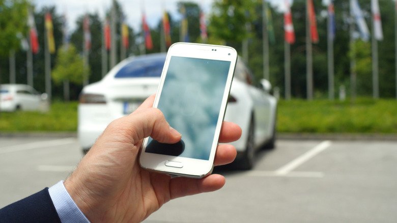 A person operating an automobile with a mobile phone.