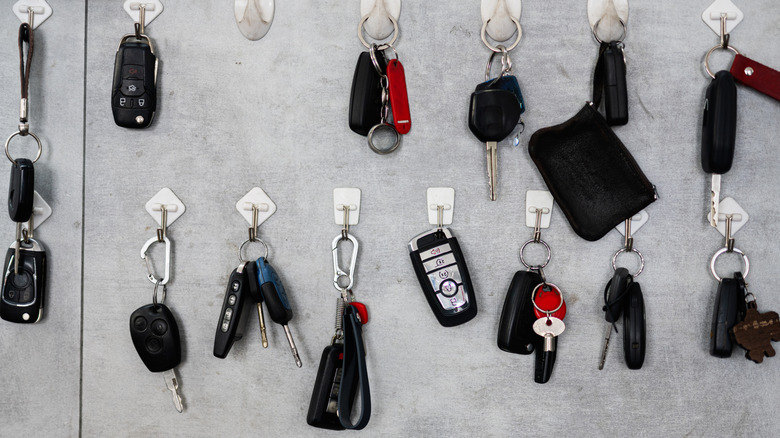 A collection car keys from several eras hanging on wall hooks.