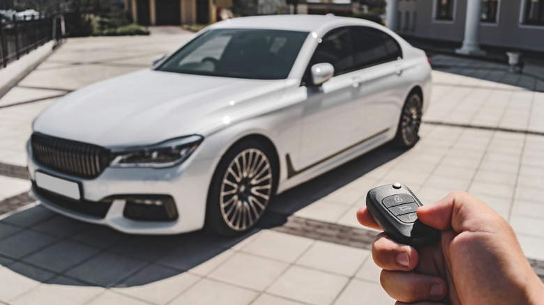 Car key fob aimed at a white automobile.
