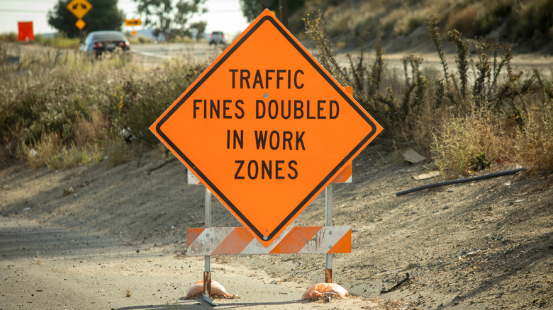 Orange traffic sign stating that traffic fines are doubled while in the posted work zone.