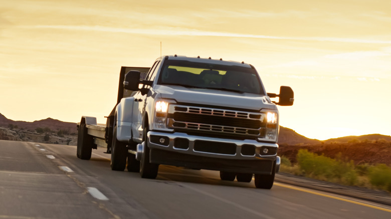 A truck driving at sunset with an attached trailer.