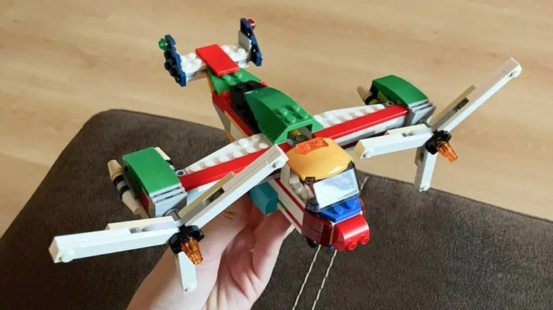 A hand holding an aircraft made of LEGO bricks