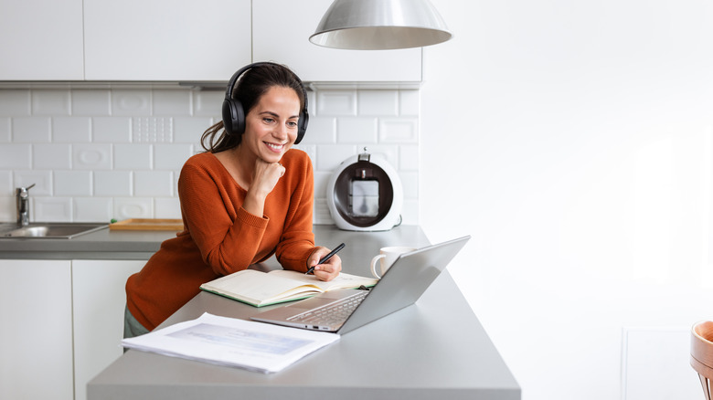 A woman taking an online course from a laptop in her kitchen