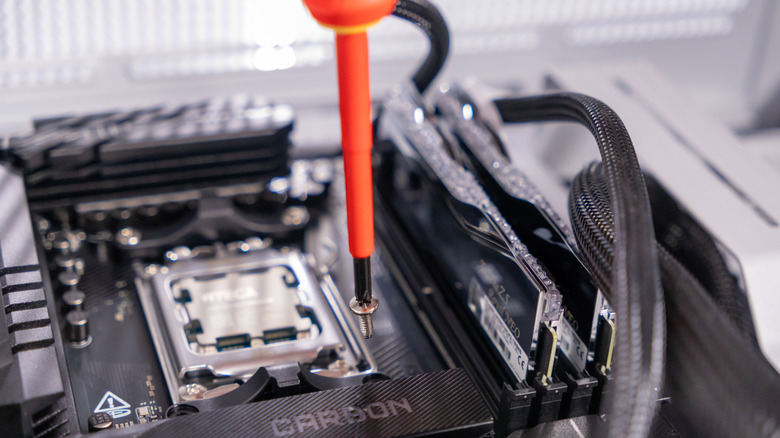 Close up of screwdriver with screw attached inside a computer