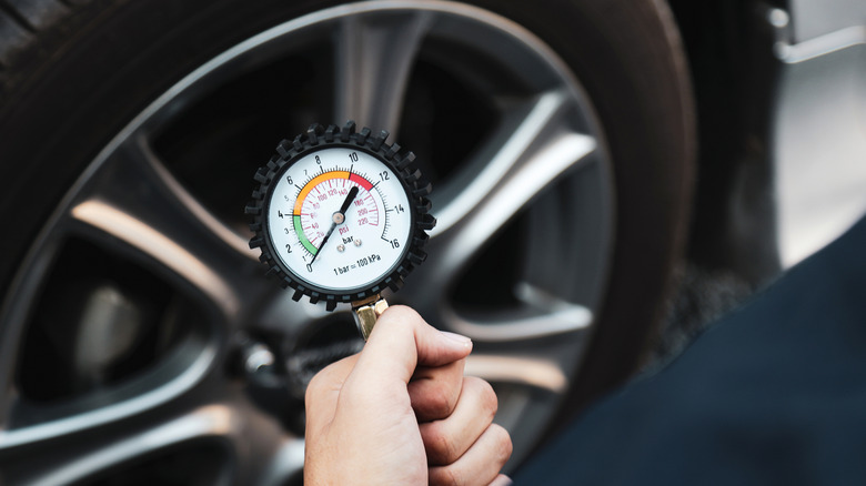 A person measuring tire pressure using a compressor with an analog pressure gauge