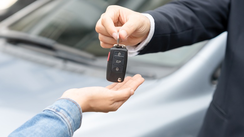 A car key being handed over to another person.