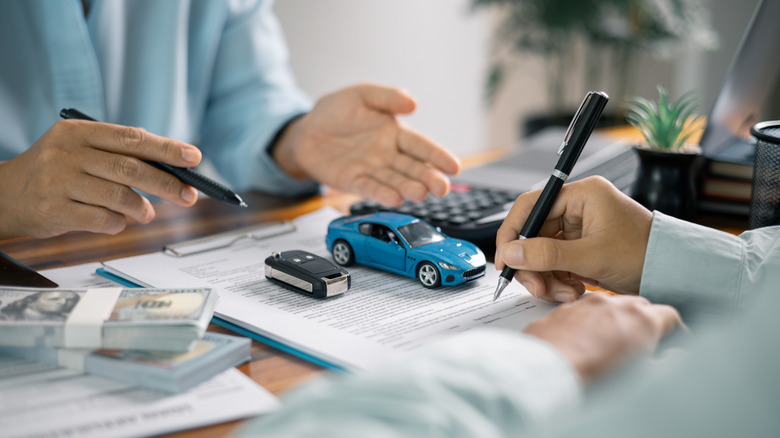 A person signing an agreement for a car purchase.