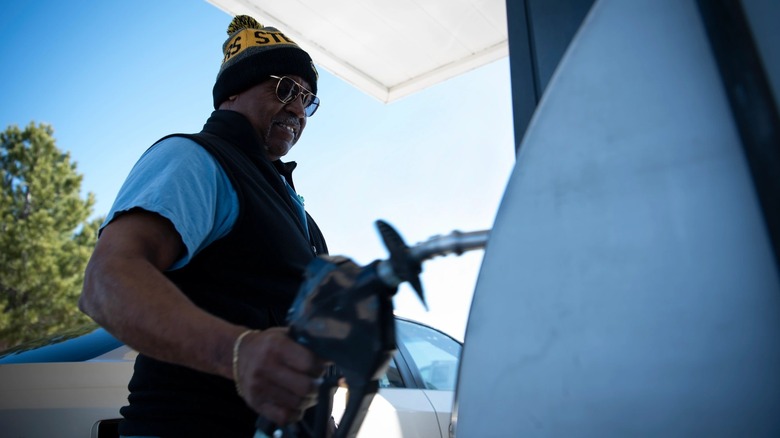 Man holding a fuel nozzle at a gas pump