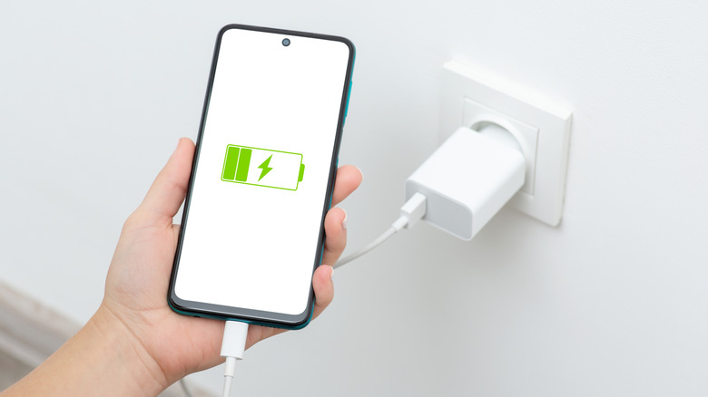 Person holding charging smartphone