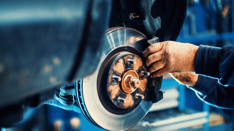 A close up of a mechanic replacing brake pads
