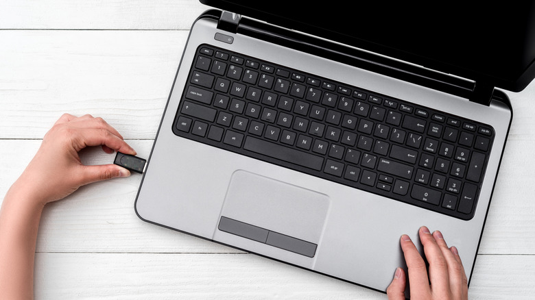 Hand removing USB drive from a laptop