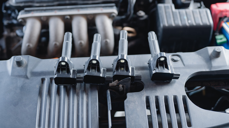 Four new ignition coils sitting near the hood latch of an unidentified car
