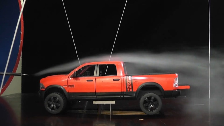 A small scale model truck being tested in a wind tunnel with its tailgate down
