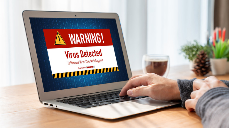 Laptop on desk showing virus detected message