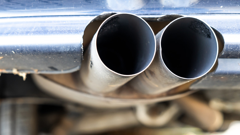 Close-up of car's exhaust pipe with dual tips extending out of a muffler