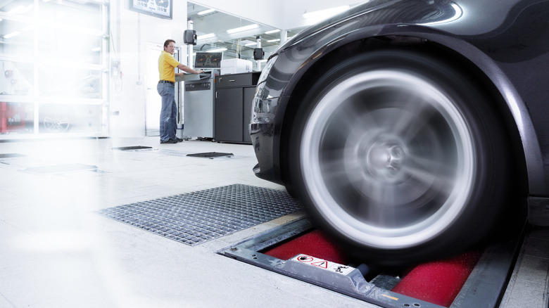 The front wheels of a car in motion, as it's being tested on a dyno