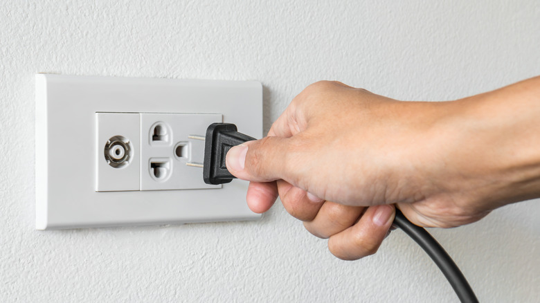 Person unplugging a power cable