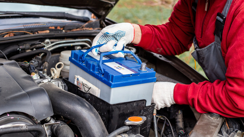 Person installing new car battery