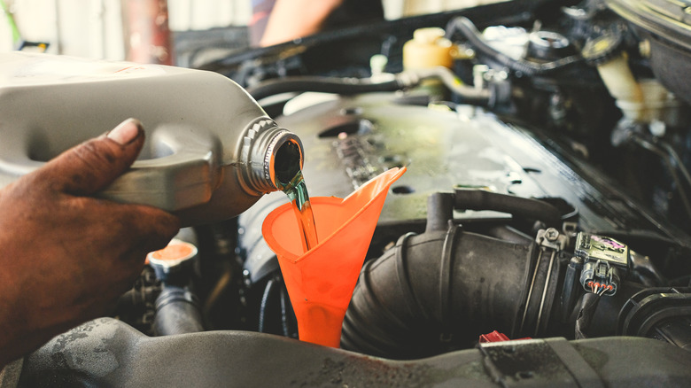 mechanic pouring transmission fluid