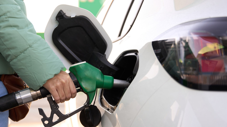 Close-up of a hand holding the diesel fuel pump while refueling the tank of a car.