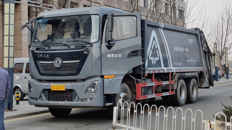 A gray Dongfeng dump truck on a city street, front 3/4 view