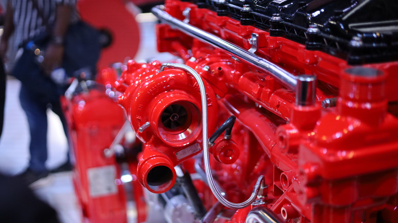 A red Cummins diesel engine on display at an expo, with the turbocharger in focus