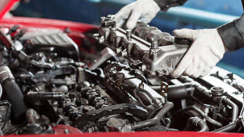 A mechanic working on a diesel engine in a red vehicle