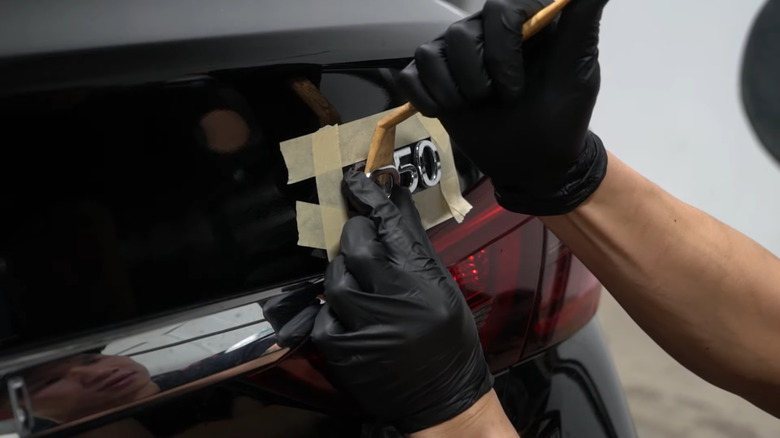 Man debadging his car using a plastic tool