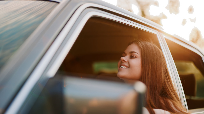 Happy young woman enjoying a summer drive with the window down