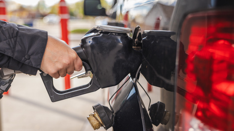 Person pumping gas into a black pickup truck