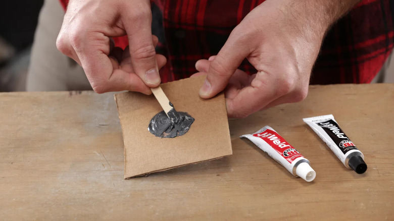 A shot of J-B Weld being used on cardboard at a work table