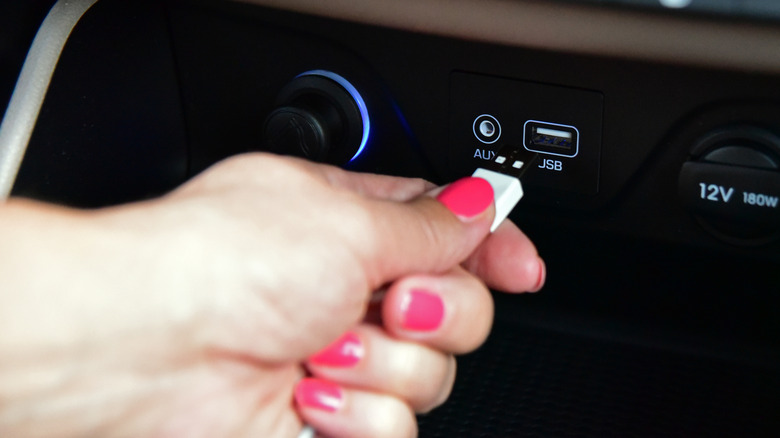 A woman plugging a USB cable into her vehicle's console