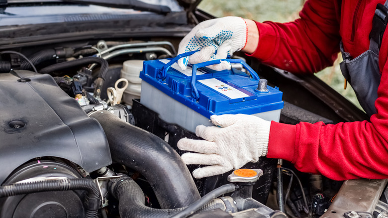 Mechanic takes a battery out of a car