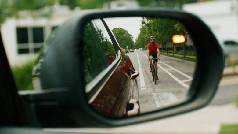 A cyclist seen in the side mirror of a Chevrolet Traverse