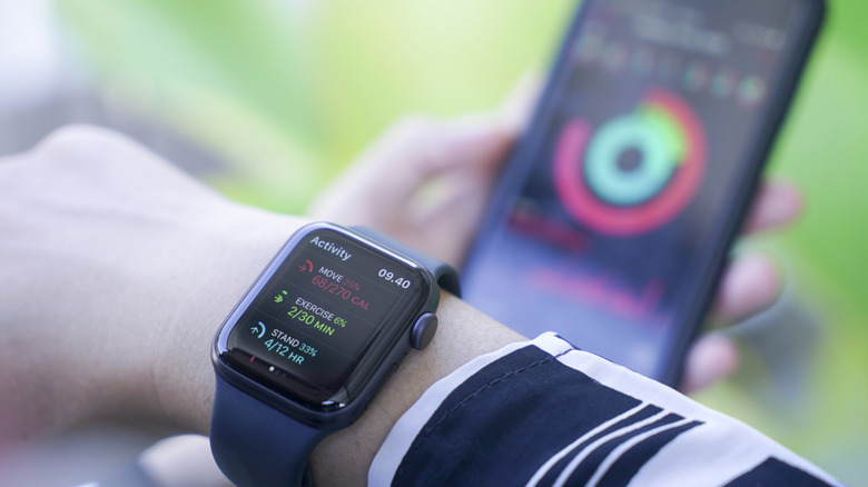 A person wearing an Apple Watch with an iPhone in the background