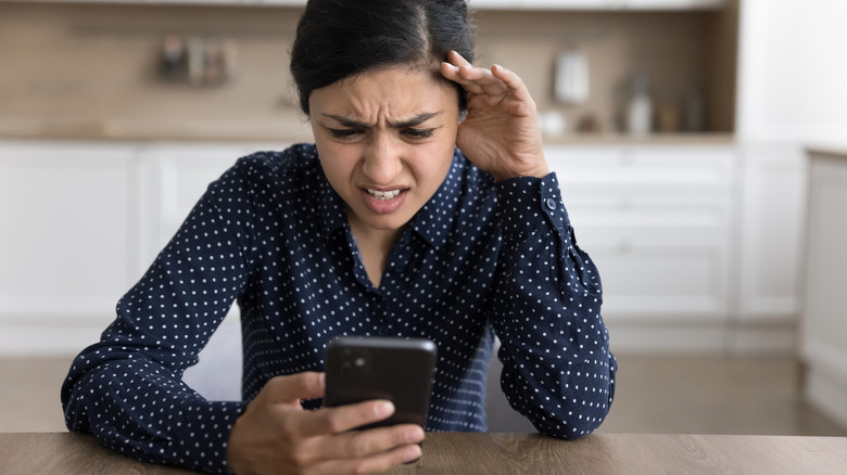 A girl looking nervous by looking at her phone.