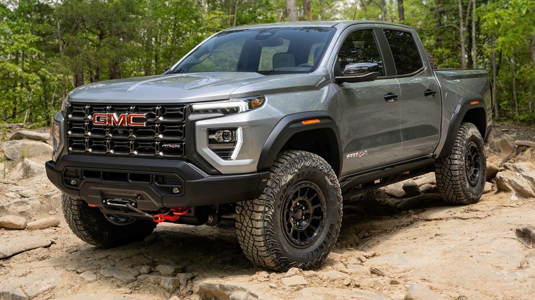 2025 GMC Canyon AT4X AEV Edition parked on a rocky terrain surrounded by trees