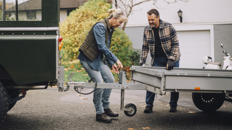 man and woman attaching a trailer to a tow hitch