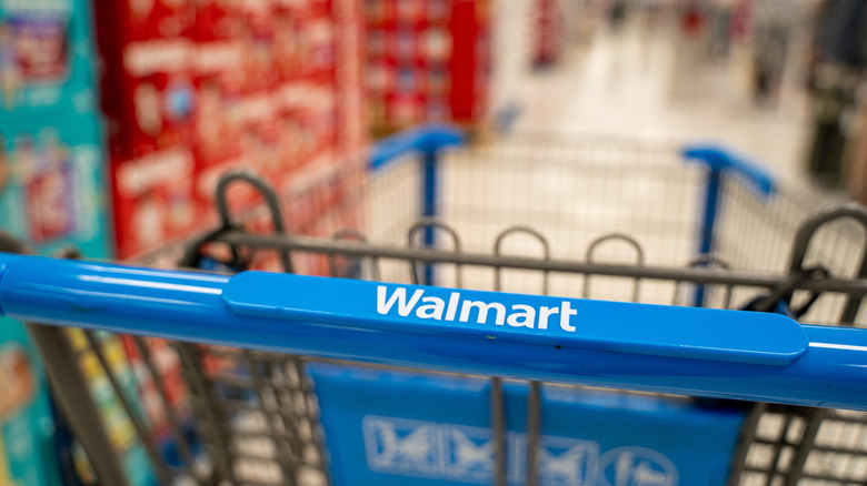 Walmart shopping cart being pushed down an aisle.