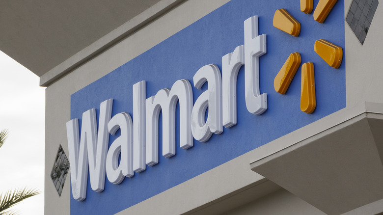 A Walmart sign beside a palm tree.
