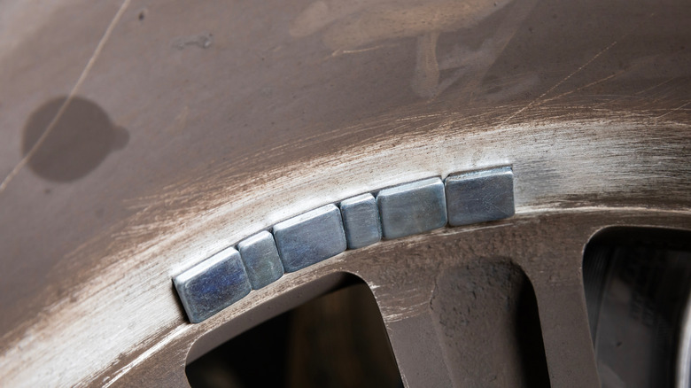 A dirty-looking tire with wheel balancing weights