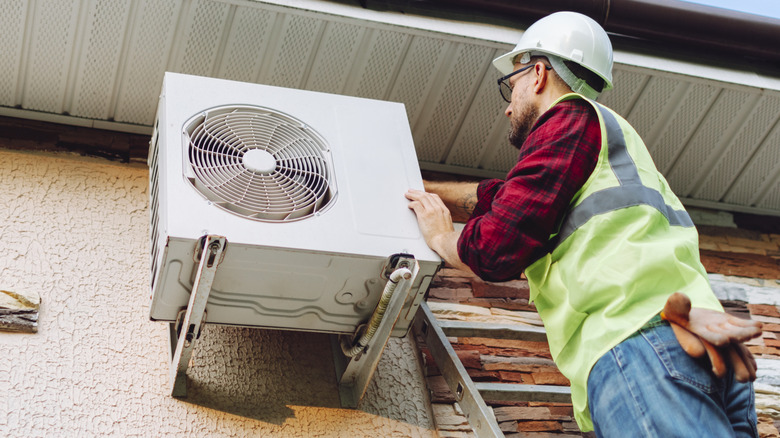 A technician in uniform repairing or inspecting a heat pump