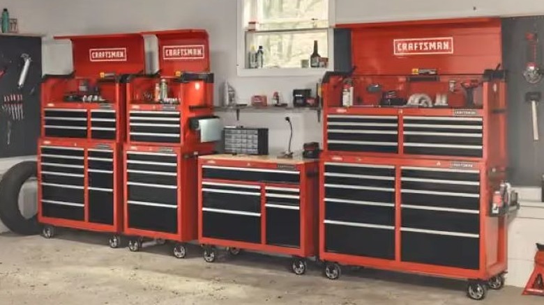 Several red and black tool boxes lined up along a garage wall