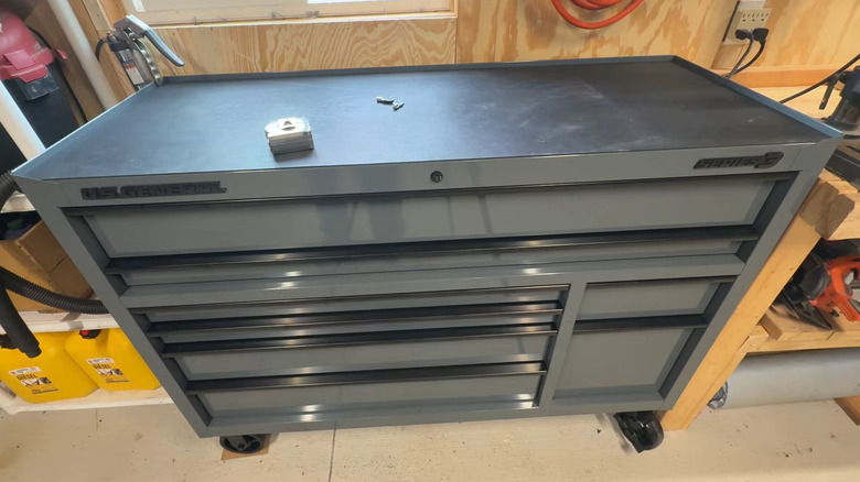 A gray tool box in a garage with wood paneled walls