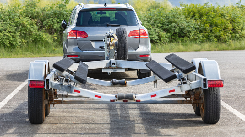 Rear view of a gray SUV in a parking lot with a boat trailer attached
