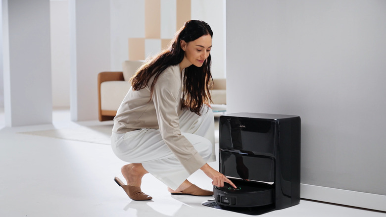 Woman crouching next to the MOVA Z60 Ultra Roller Complete at its base station