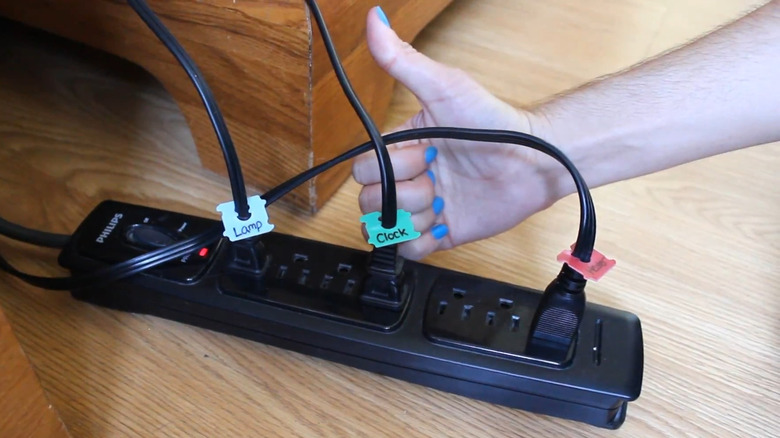 A Phillip's power strip with plugs in it each labelled with multicoloured bread tags and someone giving a thumbs up.